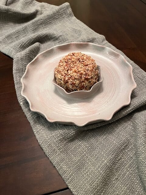 white plate with a chocolate chip cheese ball on top and a gray table runner