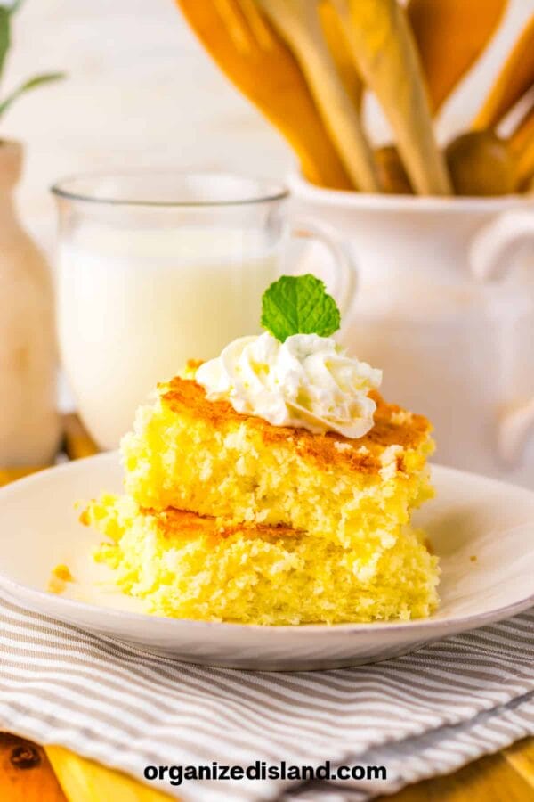 yellow cake with whipped topping and a mint sprig on top with milk in background