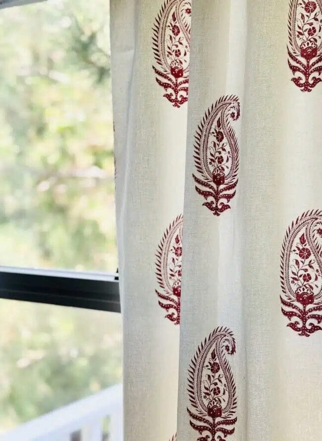 white curtain with red paisley block print hanging in window