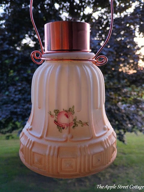 vintage light globe hanging with a copper handle outside in the open