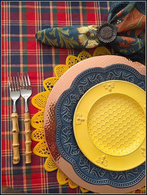plaid tablecloth with gold, blue, copper and yellow plates and silverware on table