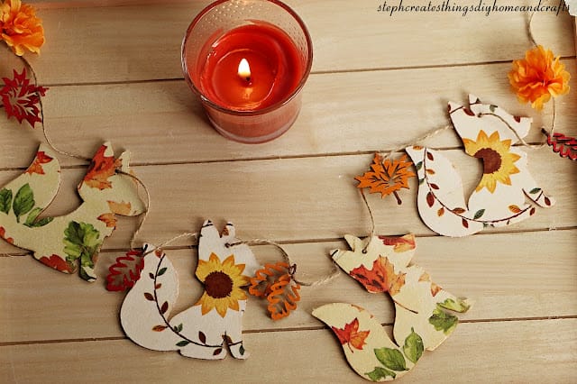 string of wood fox cutouts with floral designs on them with an orange candle