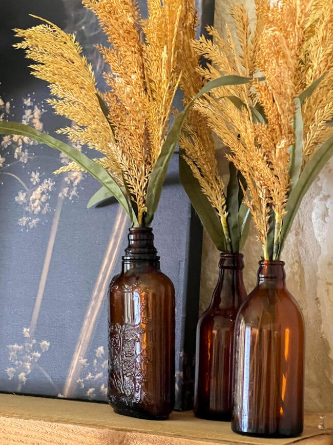 3 vintage amber bottles with faux wheat inside