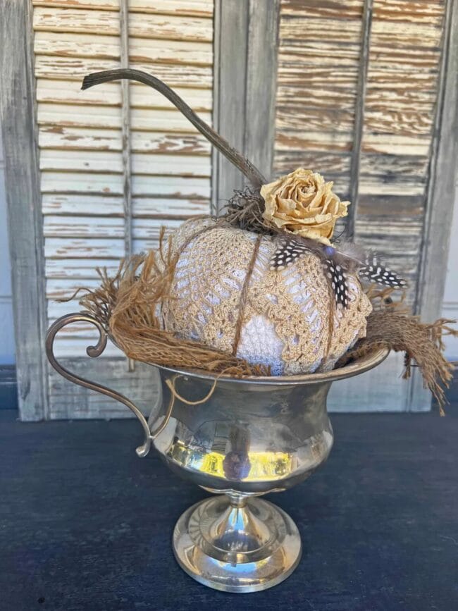 silver ice bucket with a handmade vintage looking pumpkin inside. Has a rose on top.