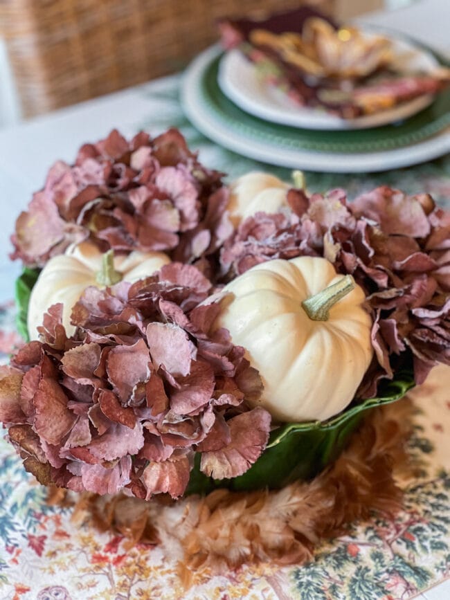 purple flowers with white pumpkins in a bowl used as a centerpiece