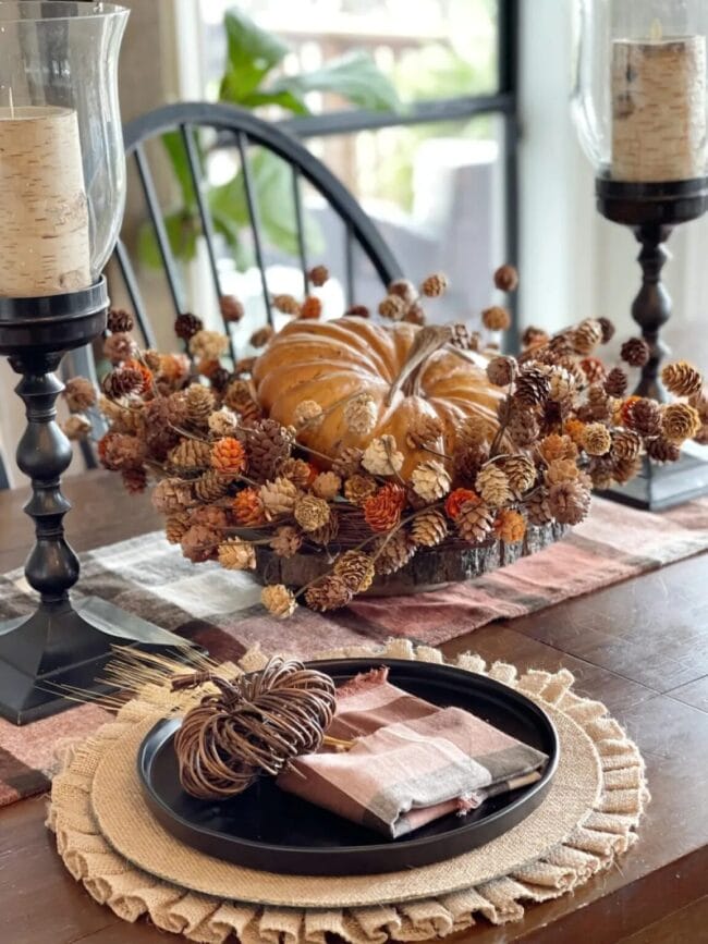 two black candlesticks with a pumpkin and hops centerpiece and a place setting with a black plate and small stick pumpkin