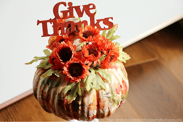 floral pumpkin with orange flowers and a Give Thanks pick tucked in on top