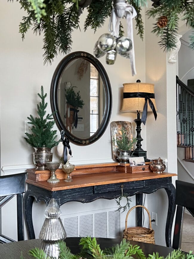 desk with mirror over top, lamp and christmas tree and silver pieces