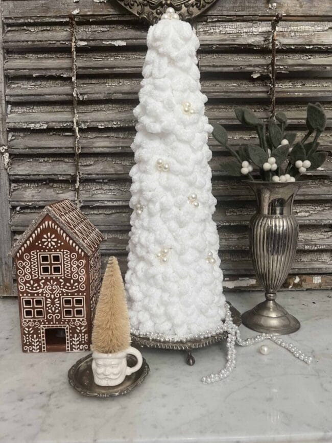 white looped Christmas tree with a gingerbread house, silver vase and Santa mug with small tree inside