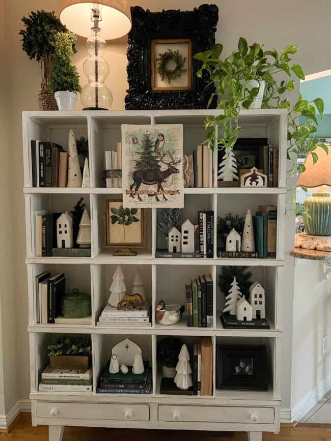 16 square cubbies with books, white ceramic houses and trees for Christmas