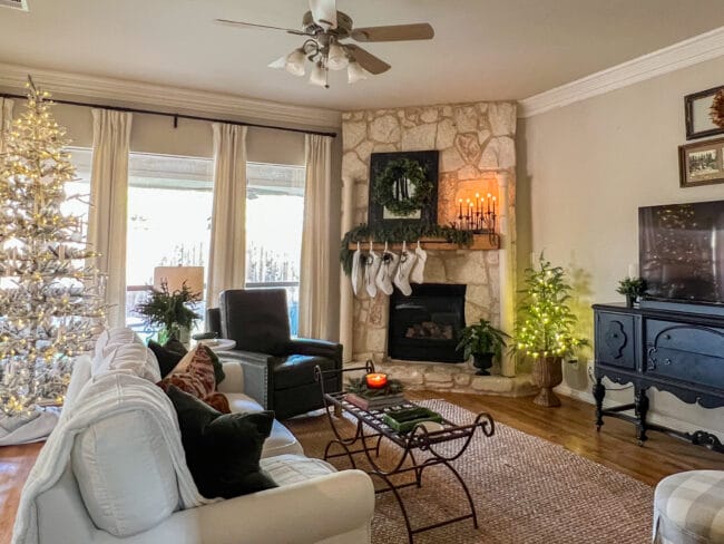 living room with stone fireplace with white stockings, and a black mirror on mantel