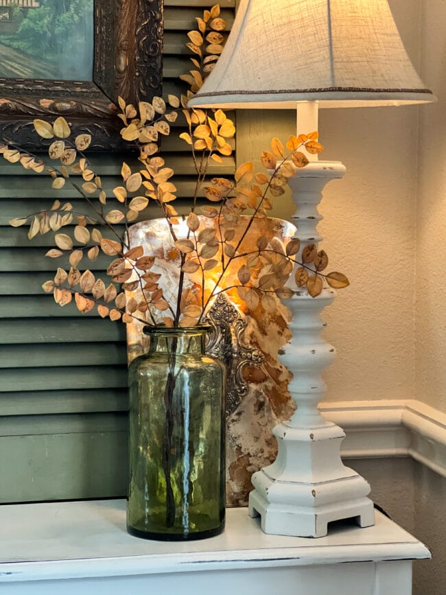 clear green case with a fall stem, white lamp and silver casserole lid behind it.