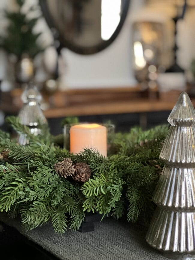 close up of greenery candle centerpiece with mercury glass trees