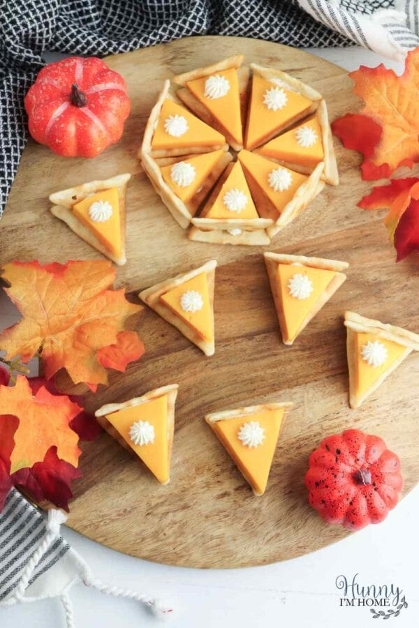 cheese and crackers made to look like a pumpkin pie on a wooden board