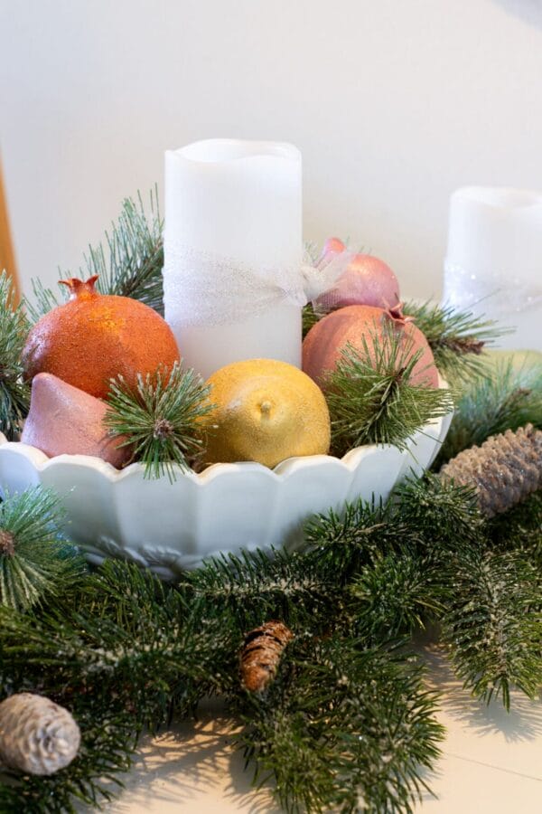 faux fruit with white candles in a centerpiece