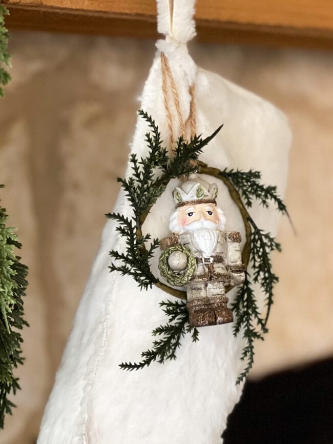 white fur stocking with a small wreath and metallic nutcracker ornament