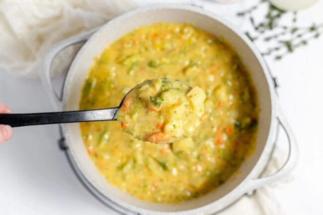 broccoli potato soup in a white bowl with spoon