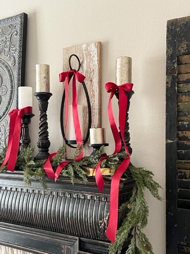 5 candles on a mantel with red bows and garland