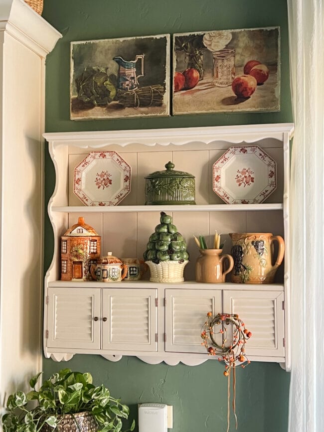 Small antique shelf hanging on kitchen wall with vintage pottery and plates in fall colors