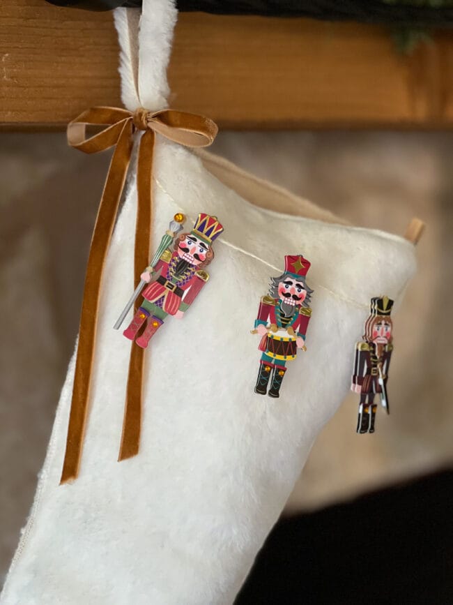 white fur stocking with a gold velvet ribbon and paper nutcrackers hanging like a garland across the top of it