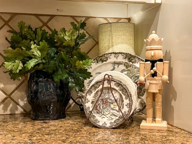 Oak leaf stems, CHristmas dishes in a rack with a Nutcracker beside them.