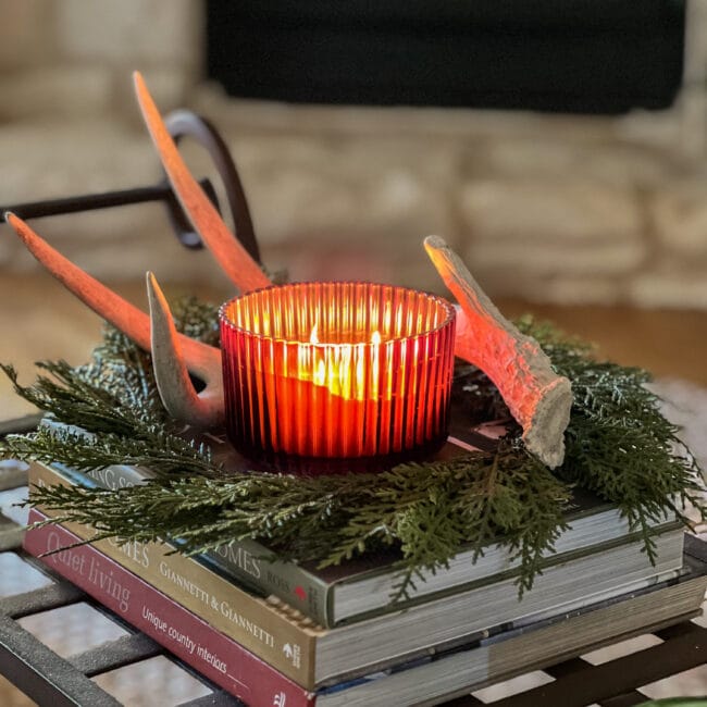 lit candle sitting on books with wreath and antlers
