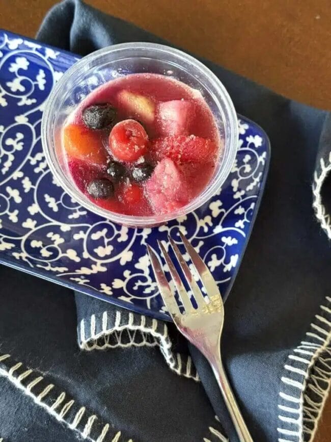 blue and white dish with a frozen fruit cup and fork on top
