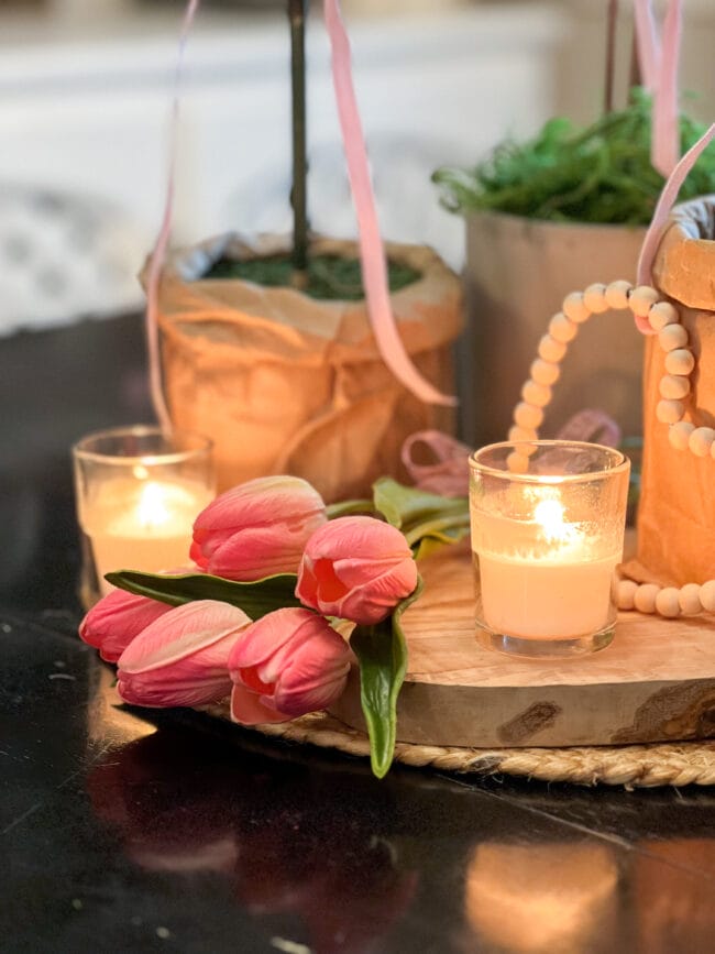 close up view of faux pink tulips laying with candles and a beaded heart