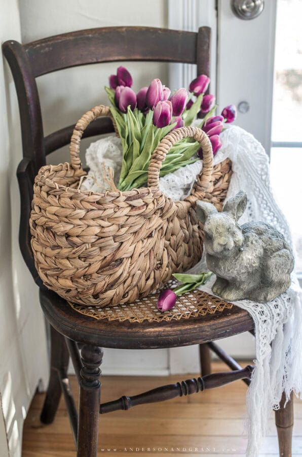 dark brown antique chair with a basket of flowers and concrete rabbit sitting on it