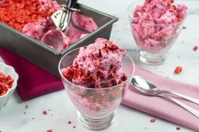 red velvet ice cream in a glass cup and a pan of it in the background