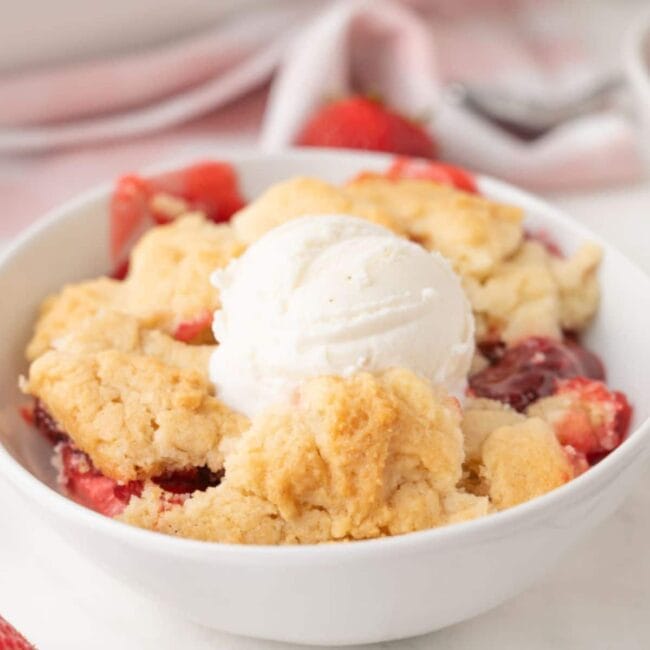 strawberry dump cake with ice cream in a white bowl