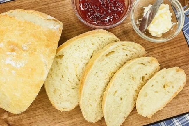 sliced homemade bread with butter and jam in little glass bowls