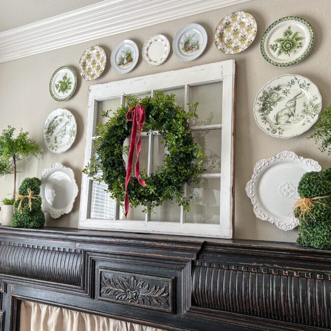 black mantel with a vintage window and wreath in center of a plate wall