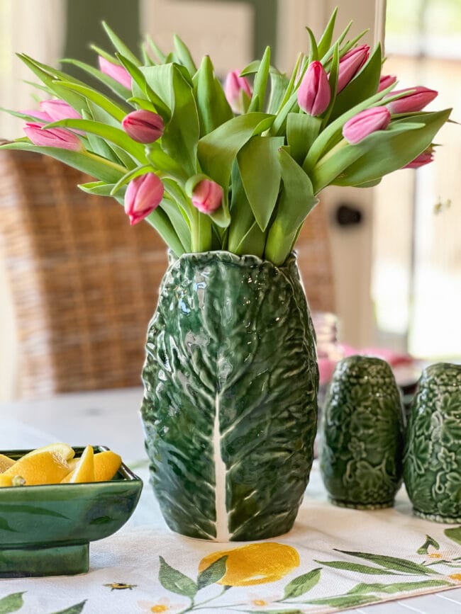 Lettuce ware vase with pink tulips, a small piece of green pottery with lemon wedges and green salt and pepper shakers