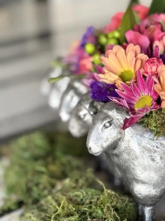 a close up photo of pink and green and purple flowers in a silver lamp container