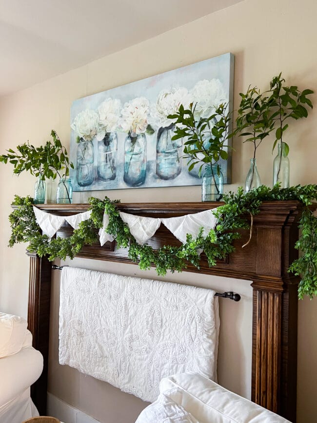 mantel with faux boxwood garland, a vintage handkerchief banner and a mason jar print hanging on wall