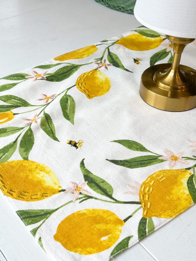 the end of a white table runner with lemons, bees and pink flowers