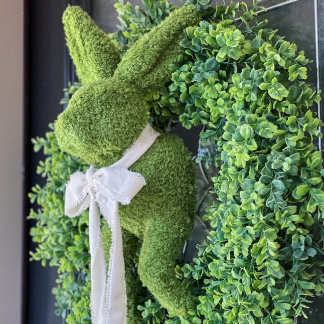 faux boxwood wreath with a half bunny body and a white bow