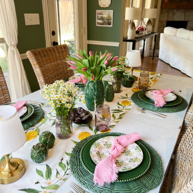 view of a tablescape with green pottery, pink and green plates, pink napkins and flowers
