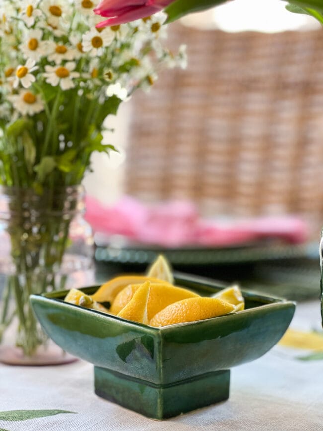 vintage green square shaped bowl with lemon wedges and flowers in the background