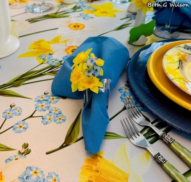 blue and yellow tablescape with plates, napkins and a floral tablecloth