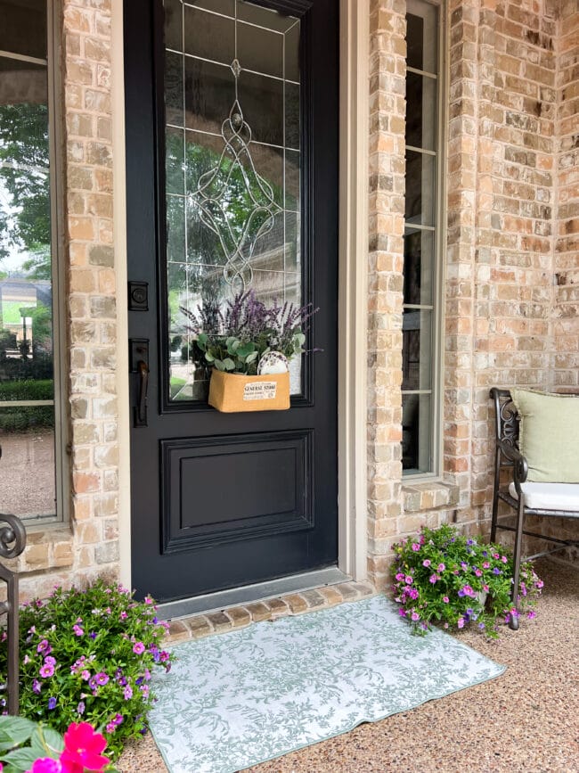 black front door on brick house with flowers on ground next to door