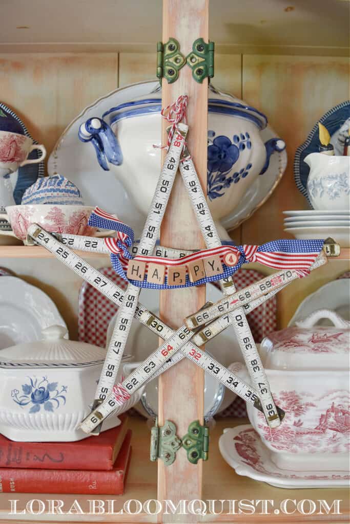 white vintage tape measure shaped like a star decorating a hutch with white and blue dishes