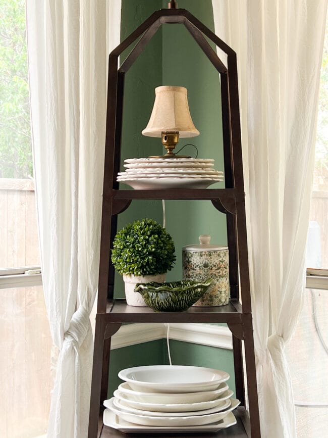 metal etagere with mini lamp, plates and a plant and leaf bowl