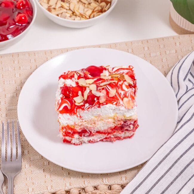 red and white piece of cake on a white plate with a fork