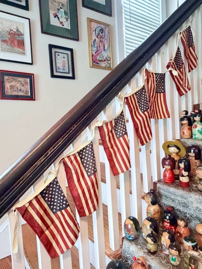 staircase railing with a banner of flags and several chinese dolls sitting next to it.