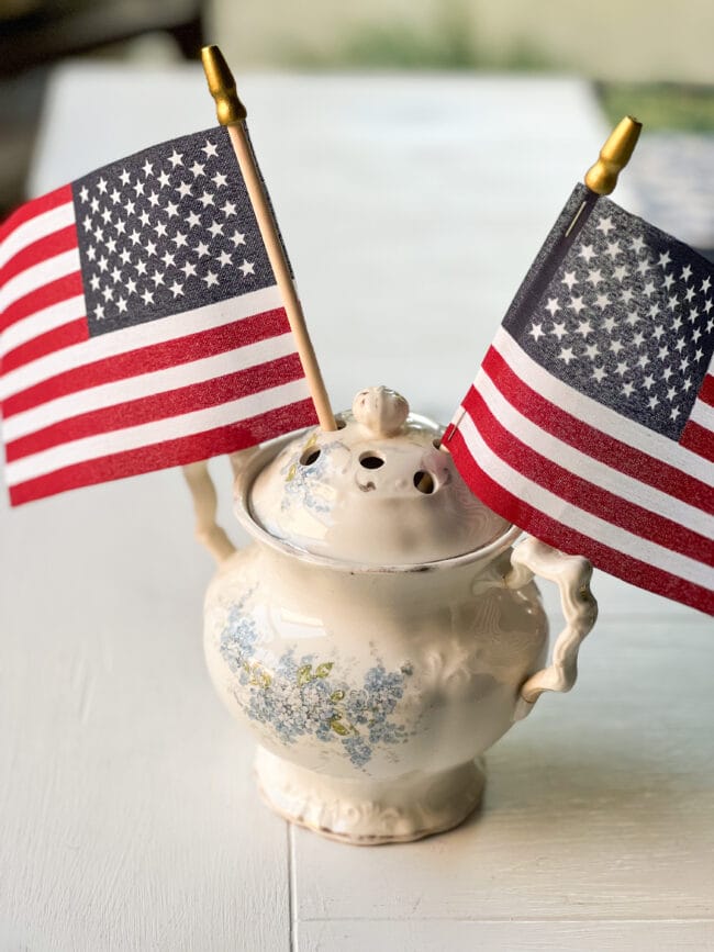 antique creamer with holes in the lid and two flags inside the holes