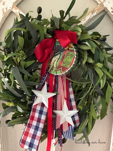 green wreath with red, white and blue ribbons, stars and a patriotic medallion hanging on it