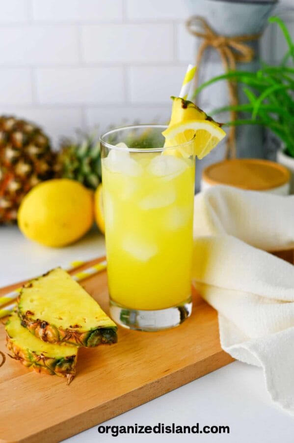 glass of pineapple lemonade with pineapples in the background