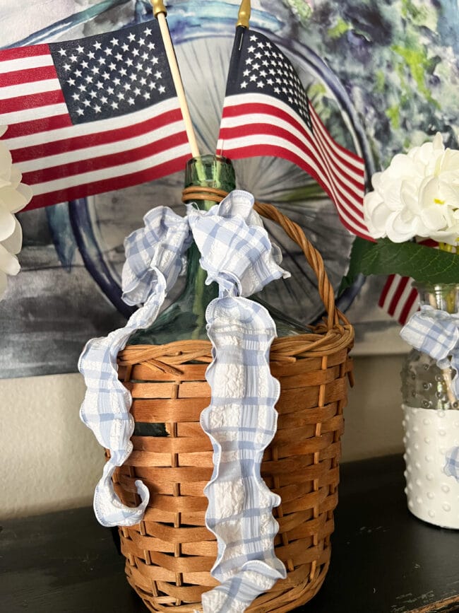 vintage demijohn with flags and blue and white bow